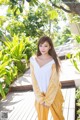 A woman in a yellow pajamas standing on a wooden deck.