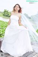 A woman in a wedding dress sitting on a wooden bridge.