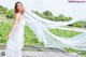 A woman in a white dress standing on a wooden bridge.