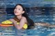 A woman in a swimming pool holding an inflatable toy.