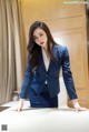 A woman in a blue suit leaning on a table.