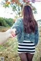 A woman holding the hand of a man in a striped skirt.