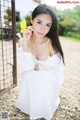 A woman in a white dress holding a yellow flower.