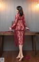 A woman in a red lingerie standing next to a table.