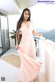 A woman in a pink dress standing on a balcony.