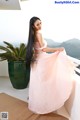 A woman in a pink dress standing on a balcony.