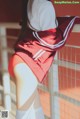 A woman in a red and white hoodie leaning against a fence.