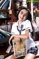 A woman in a school uniform holding a book.