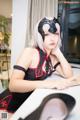 A woman in a black and red outfit sitting at a table.