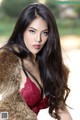 A woman in a red bra and fur coat posing for a picture.