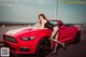 A woman sitting on top of a red convertible car.