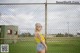 A woman standing in front of a chain link fence.