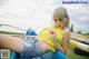 A woman in a yellow top and denim shorts sitting on a blue boat.