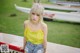 A woman in a yellow top and denim shorts sitting on a boat.