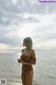 A woman standing on a beach next to the ocean.