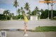 A woman standing in the middle of a street with palm trees.