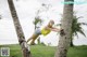 A woman leaning against a palm tree in a park.