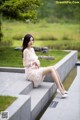 A woman sitting on the steps of a pond in a park.