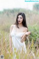 A woman in a white dress standing in tall grass.