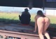 A naked woman sitting on a train track next to a man.