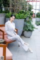 A woman sitting on a chair in a white suit.