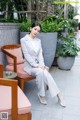 A woman in a white suit sitting on a chair.