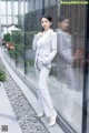 A woman in a gray suit standing in front of a glass wall.