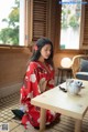 A woman in a red kimono sitting at a table.