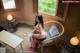 A woman sitting on a chair in front of a window.