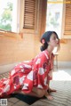 A woman in a red kimono sitting on the floor.