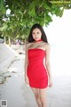 A woman in a red dress standing on a beach.