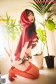 A woman in a red hooded outfit sitting on a table.