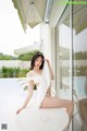 A woman in a white dress sitting on a white chair.