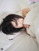 A woman laying in bed with her head under a pillow.