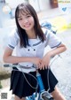 A young woman in a school uniform riding a bike.