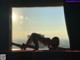 A woman laying on a window sill in front of a window.