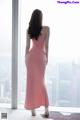 A woman in a pink dress looking out a window.