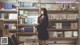 A woman standing in front of a bookshelf filled with books.