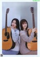 A couple of women sitting next to each other holding guitars.