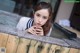 A woman leaning over a wooden wall with her hand on her chin.