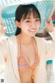 A woman in a bikini holding a laundry basket.