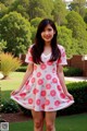 A young woman in a pink dress posing for a picture.