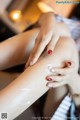 A woman is applying cream on her legs. 