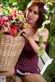 A woman sitting on a bench holding a basket of flowers.