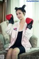 A woman sitting on a couch wearing boxing gloves.