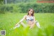 A woman in a bikini sitting in a field of grass.