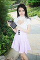 A woman in a pink and white dress holding a tablet computer.