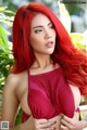 A woman with long red hair wearing a red bra.