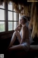 A woman in a white lingerie sitting on a window sill.