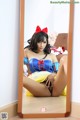 A woman in a snow white costume sitting in front of a mirror.